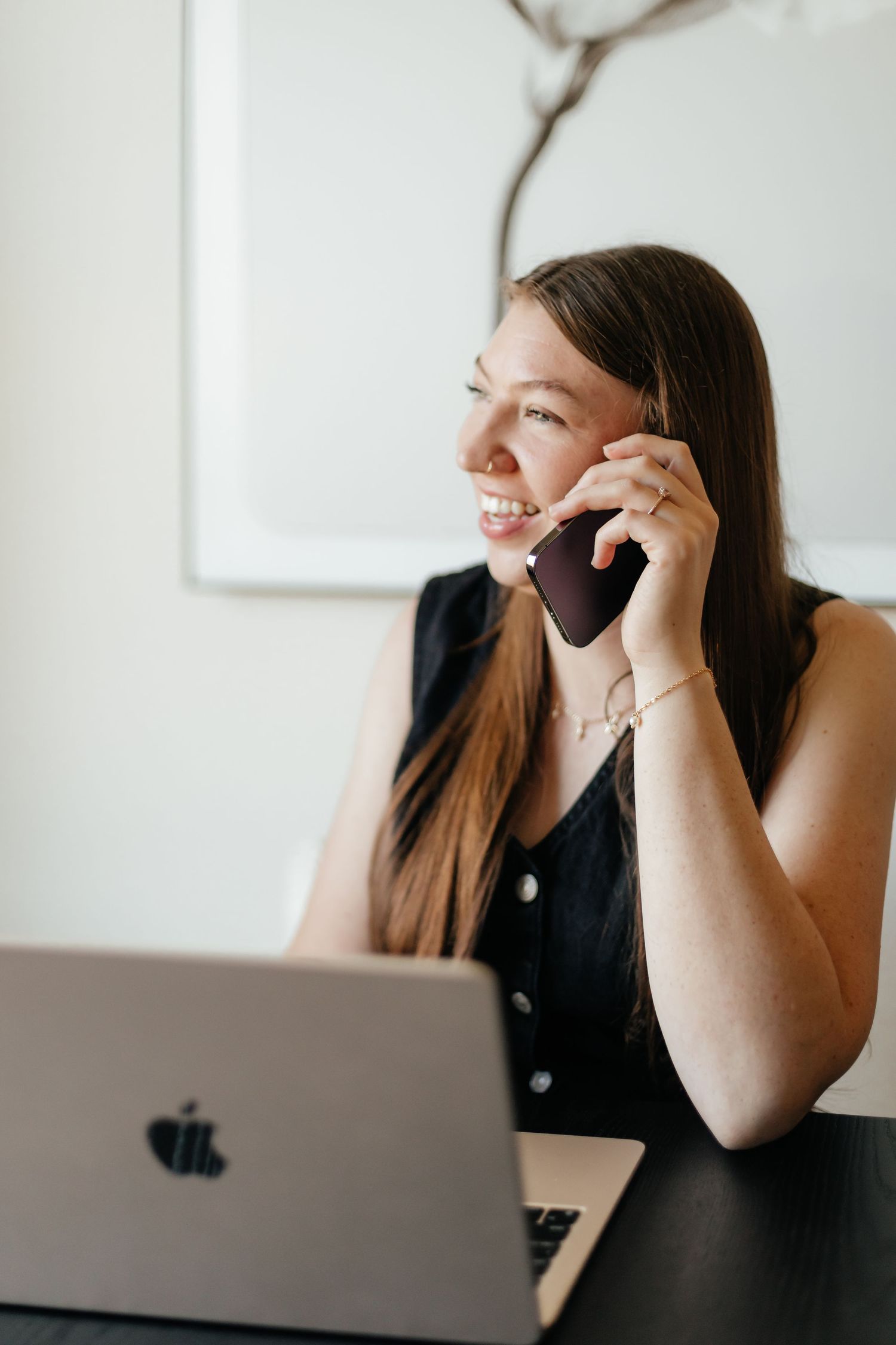 realtor holding cell phone to ear talking to client with laptop in front of her