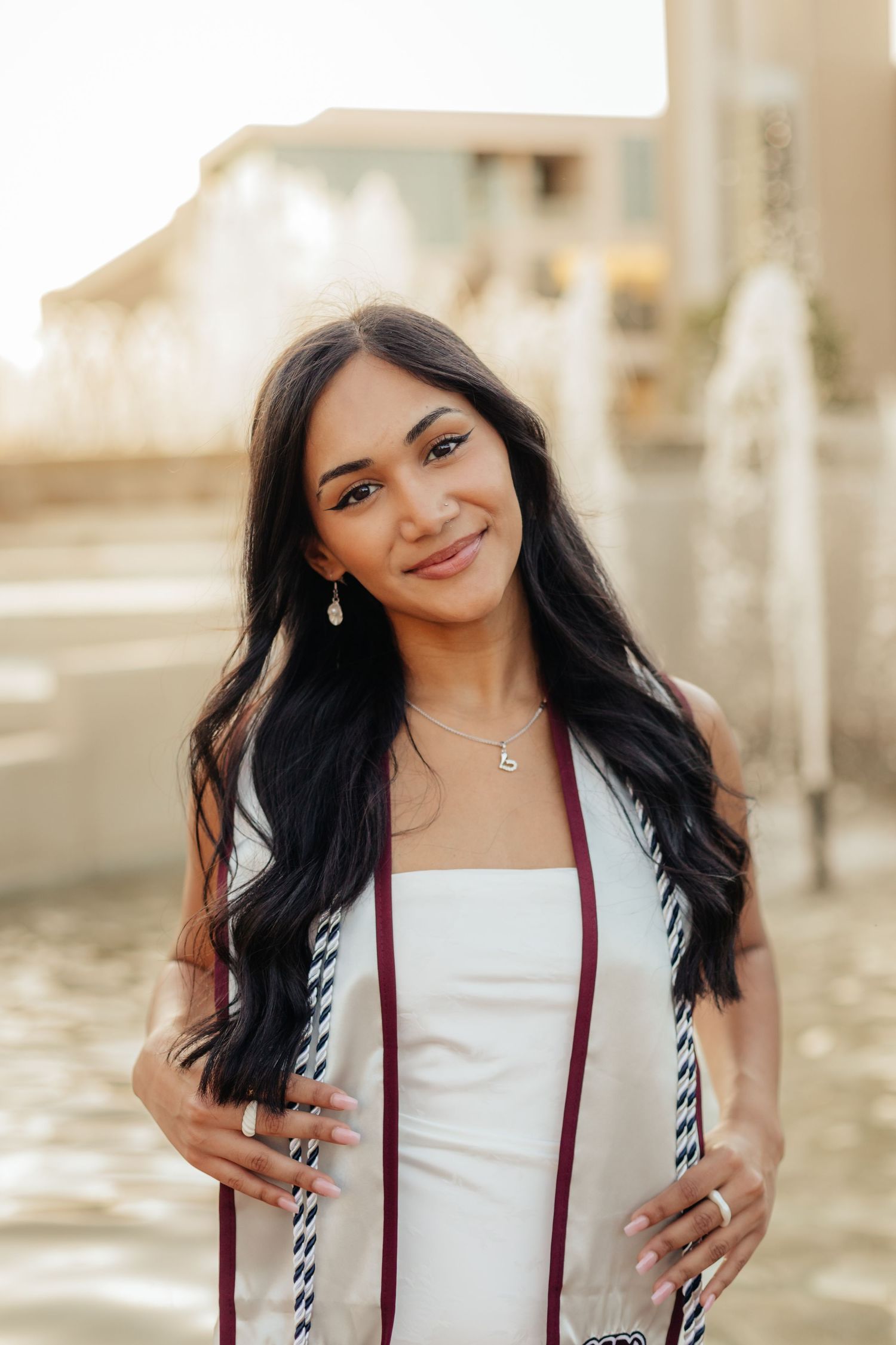 MSU grad smiling softly at camera while holding stole and cords