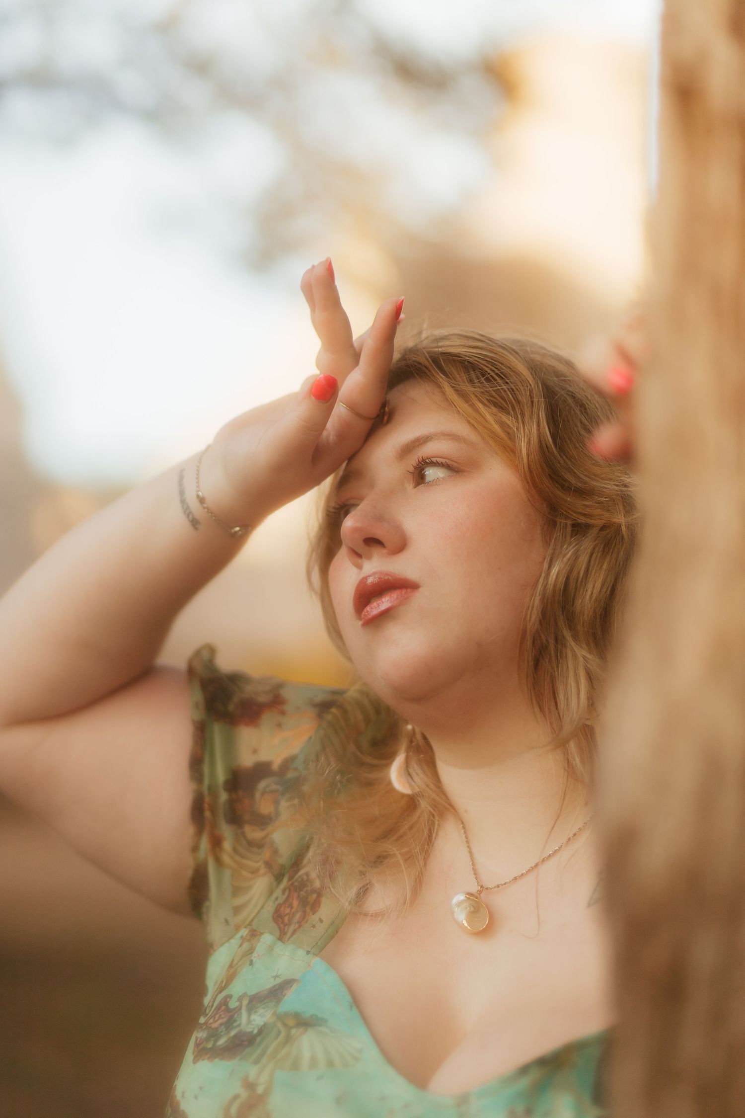 woman holding onto tree in whimsical dress looking off into distance