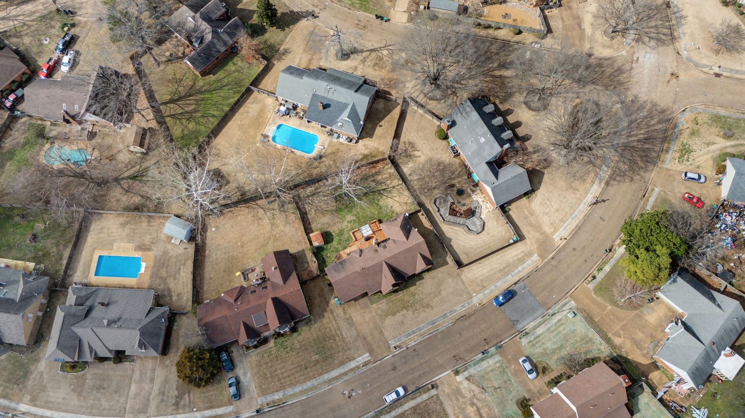 Aerial view of suburban neighborhood with swimming pools and residential houses in winter landscape.