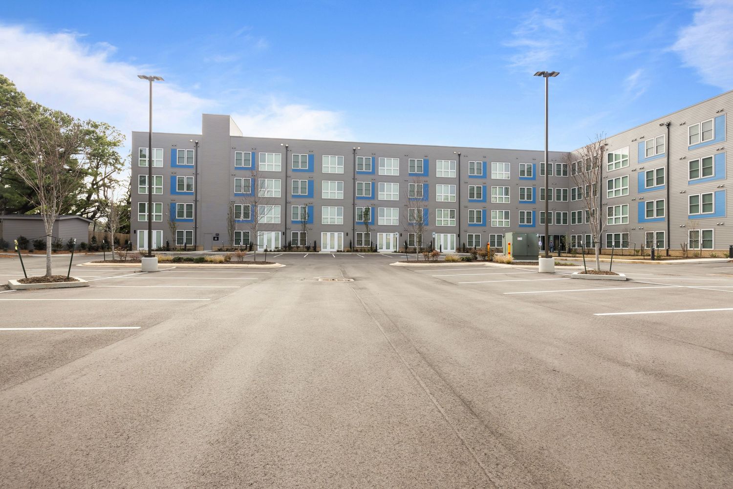Large commercial building complex with extensive parking lot under blue sky.