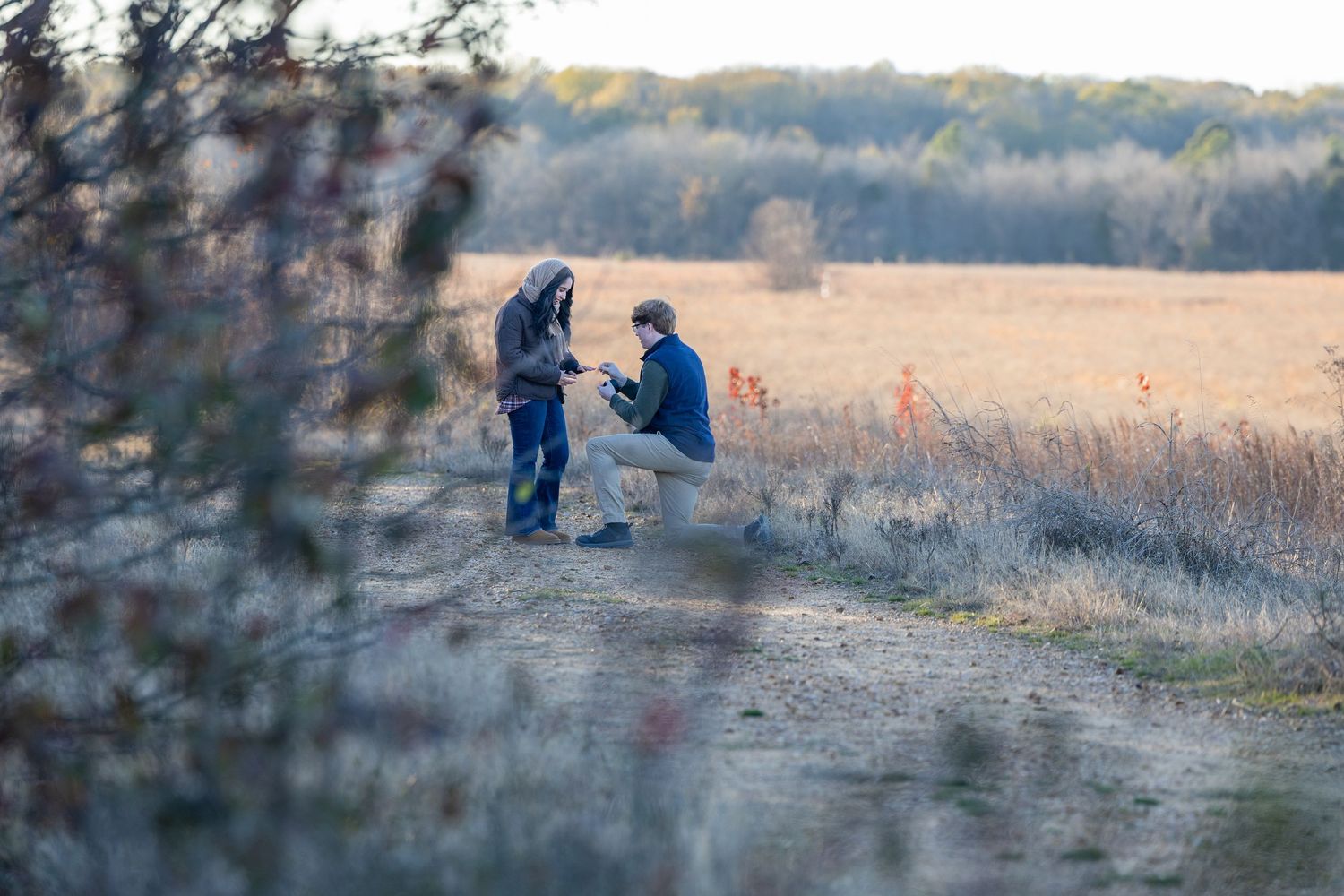 Two people share an intimate moment on a nature trail at dusk.