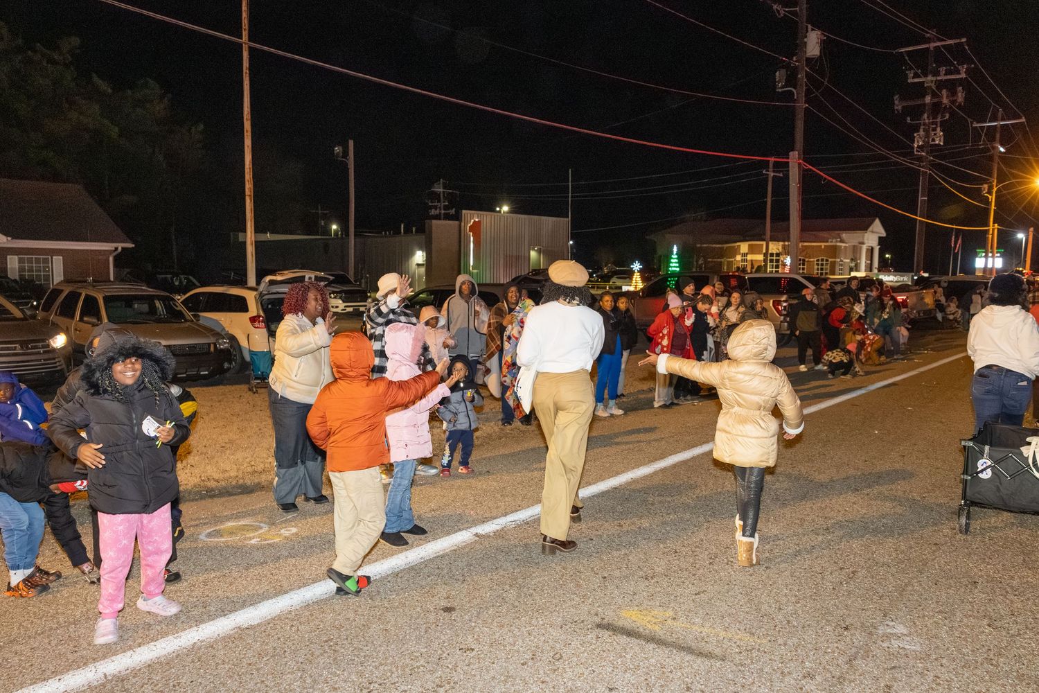 Crowd of people walking along a street at night during a community gathering.