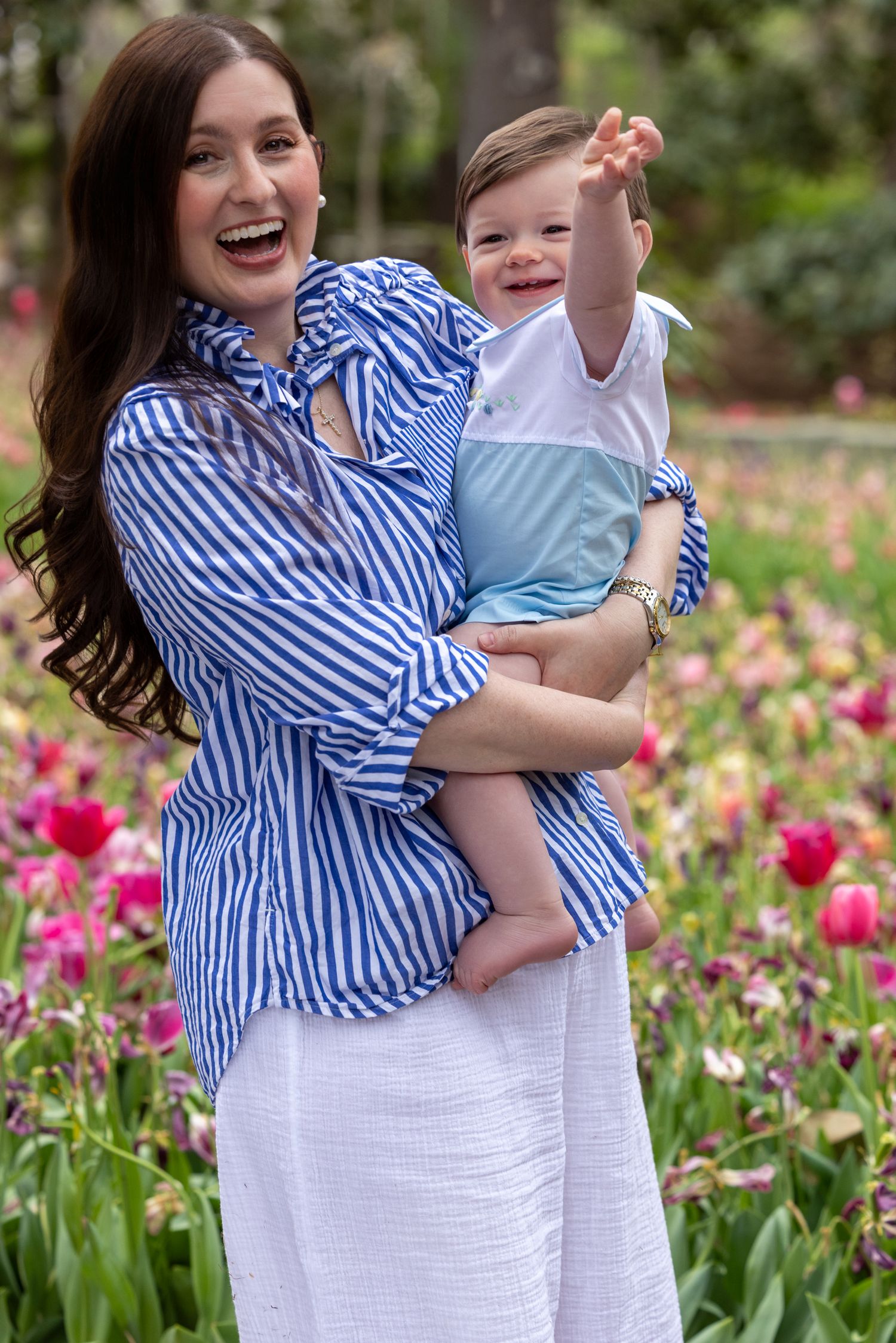 A joyful scene in a spring tulip garden with blue and white striped clothing against vibrant pink blooms.
