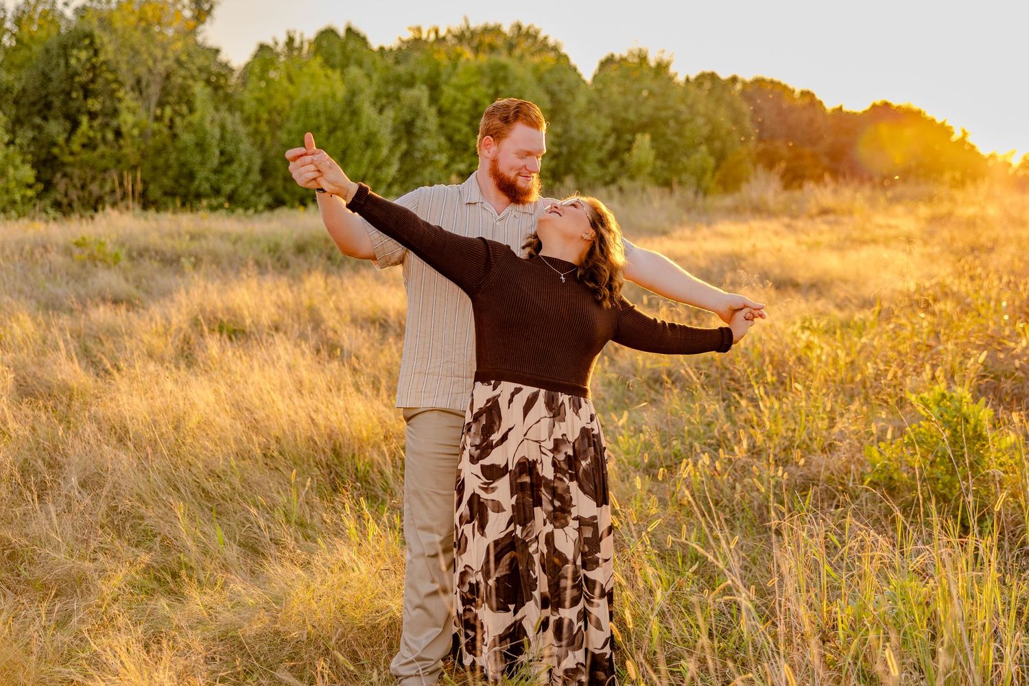 Dancing together in a field with beautiful sunset colors in background.