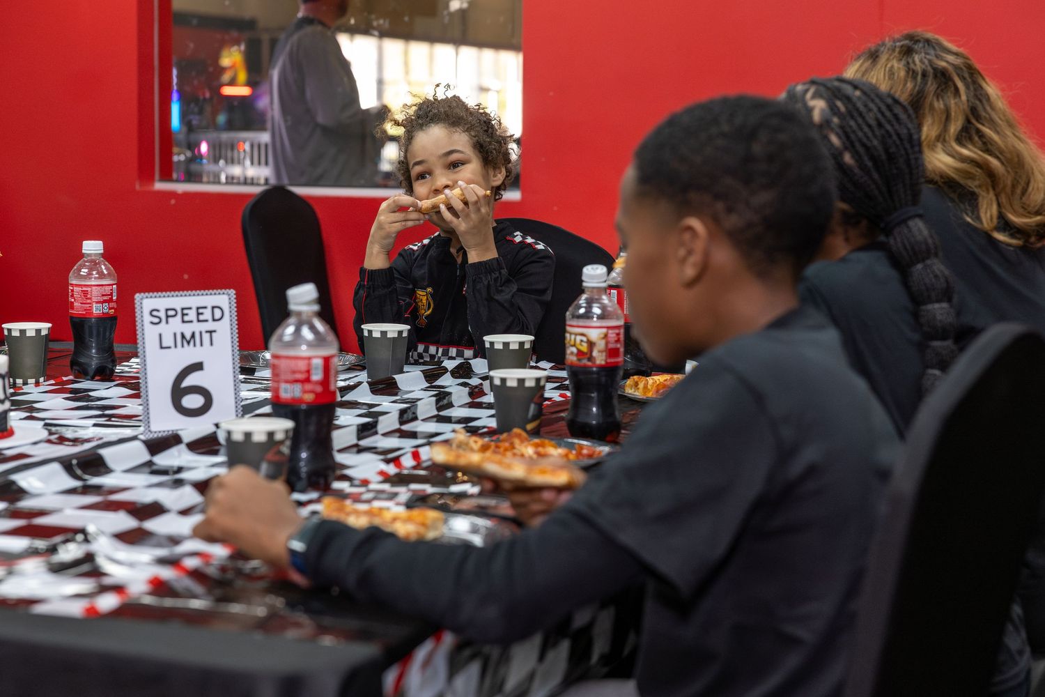 Young people engaged in a competitive chess match with drinks and snacks on a checkered table.
