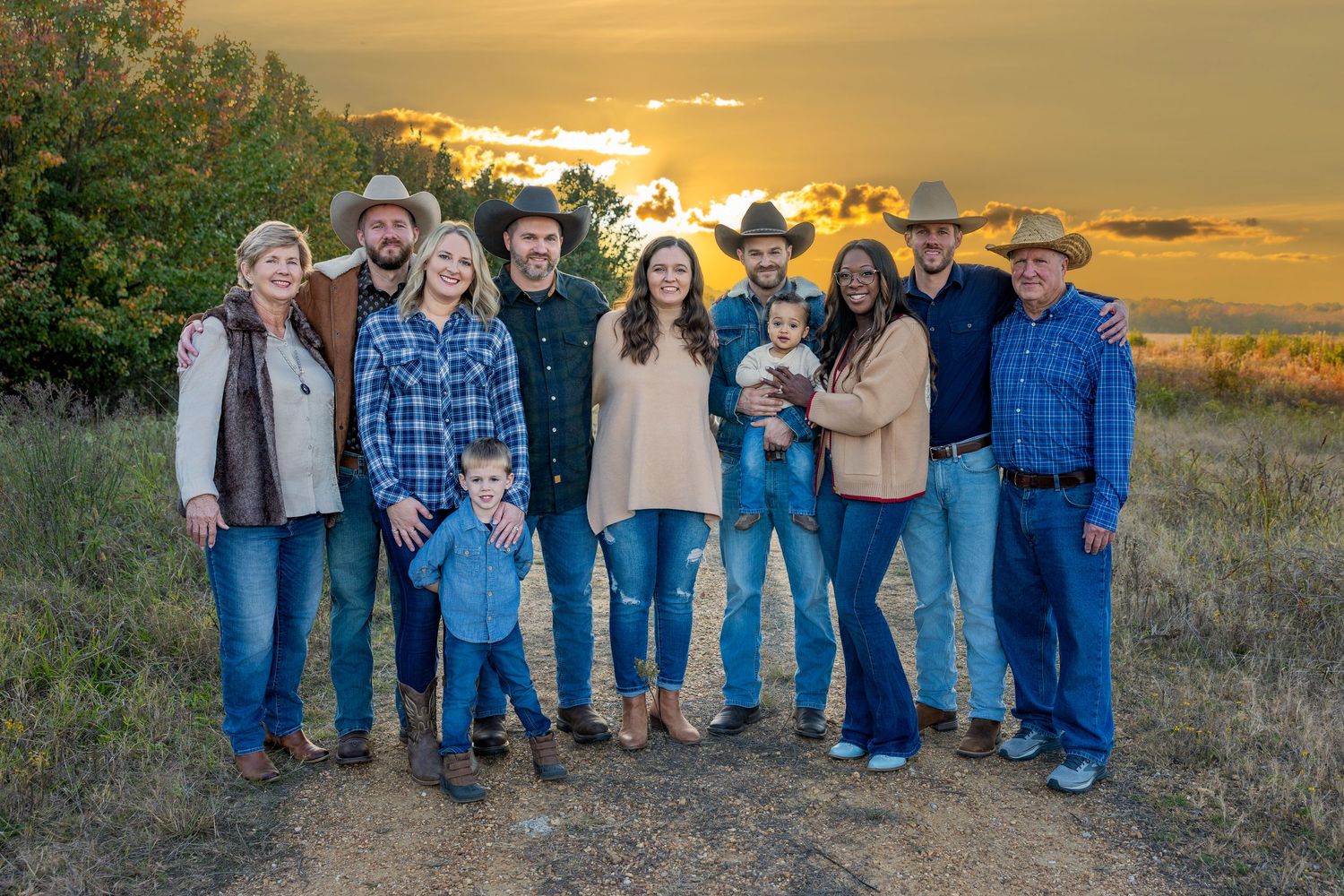 Large group portrait with coordinated blue denim outfits during sunset.