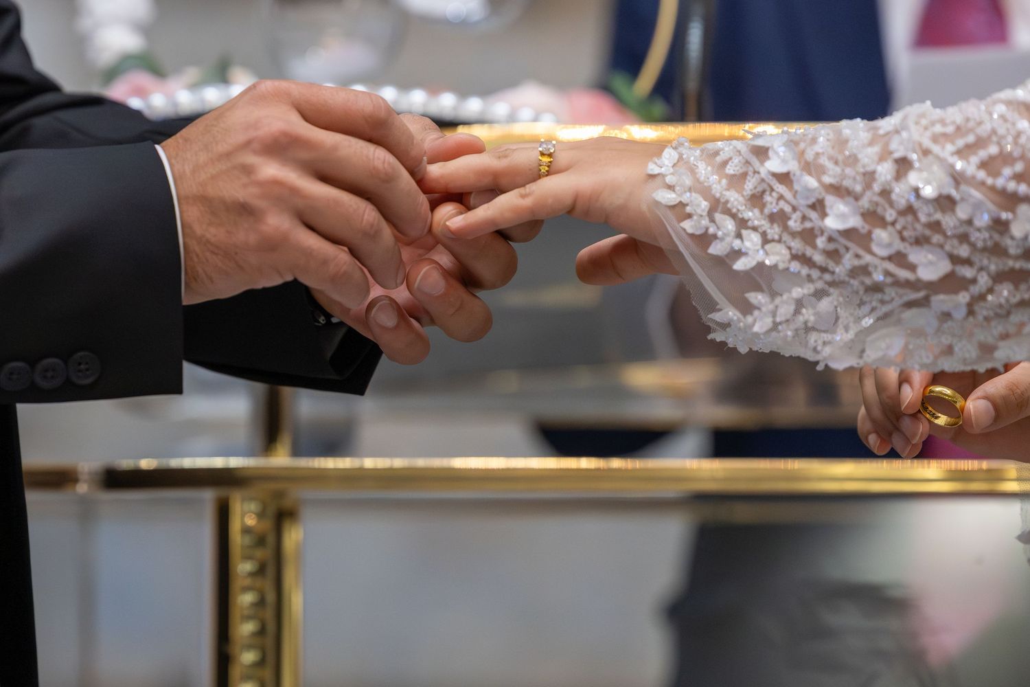 Wedding ring exchange ceremony with close-up of hands and delicate lace details.
