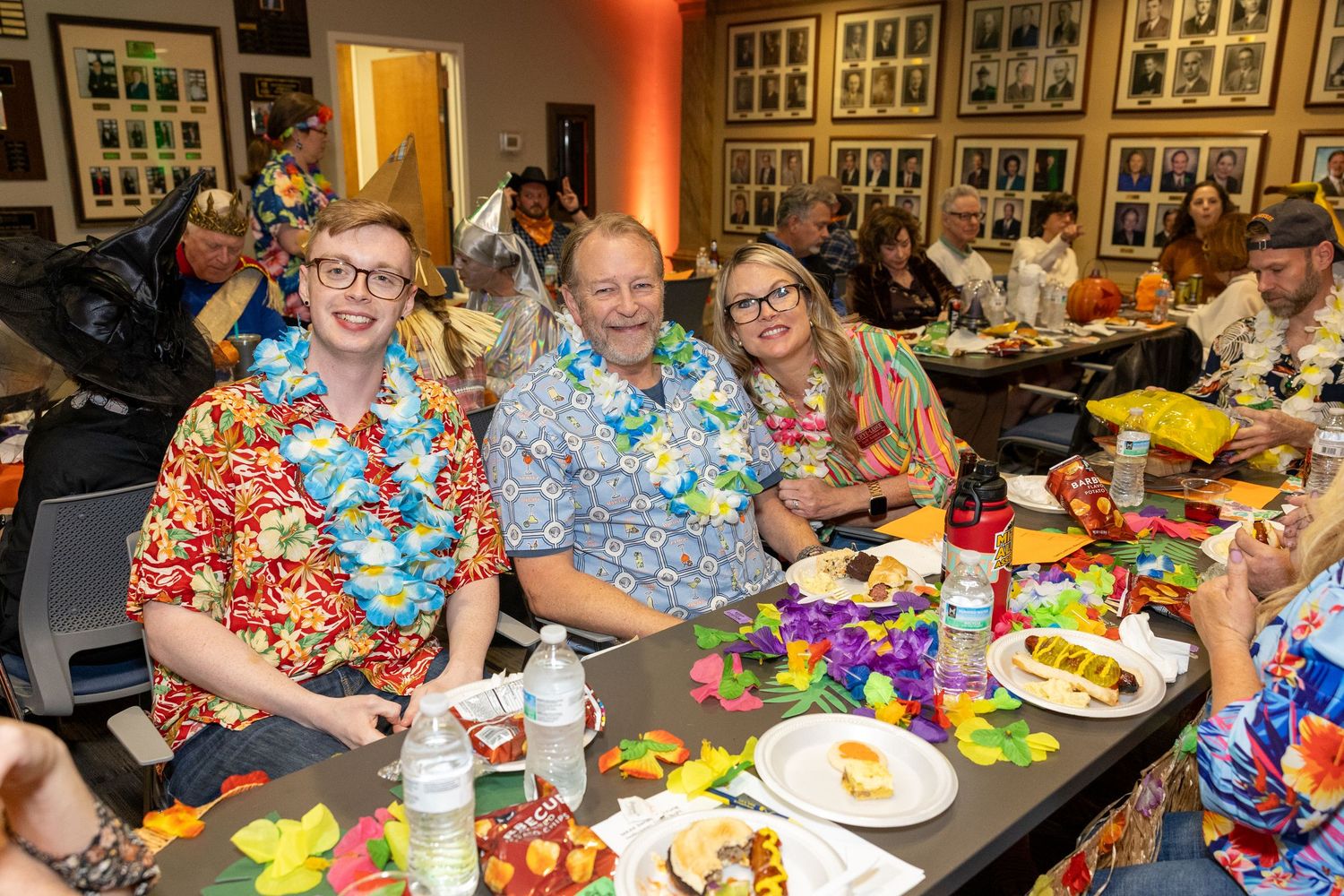 People seated at long tables decorated with tropical party favors and colorful accessories.