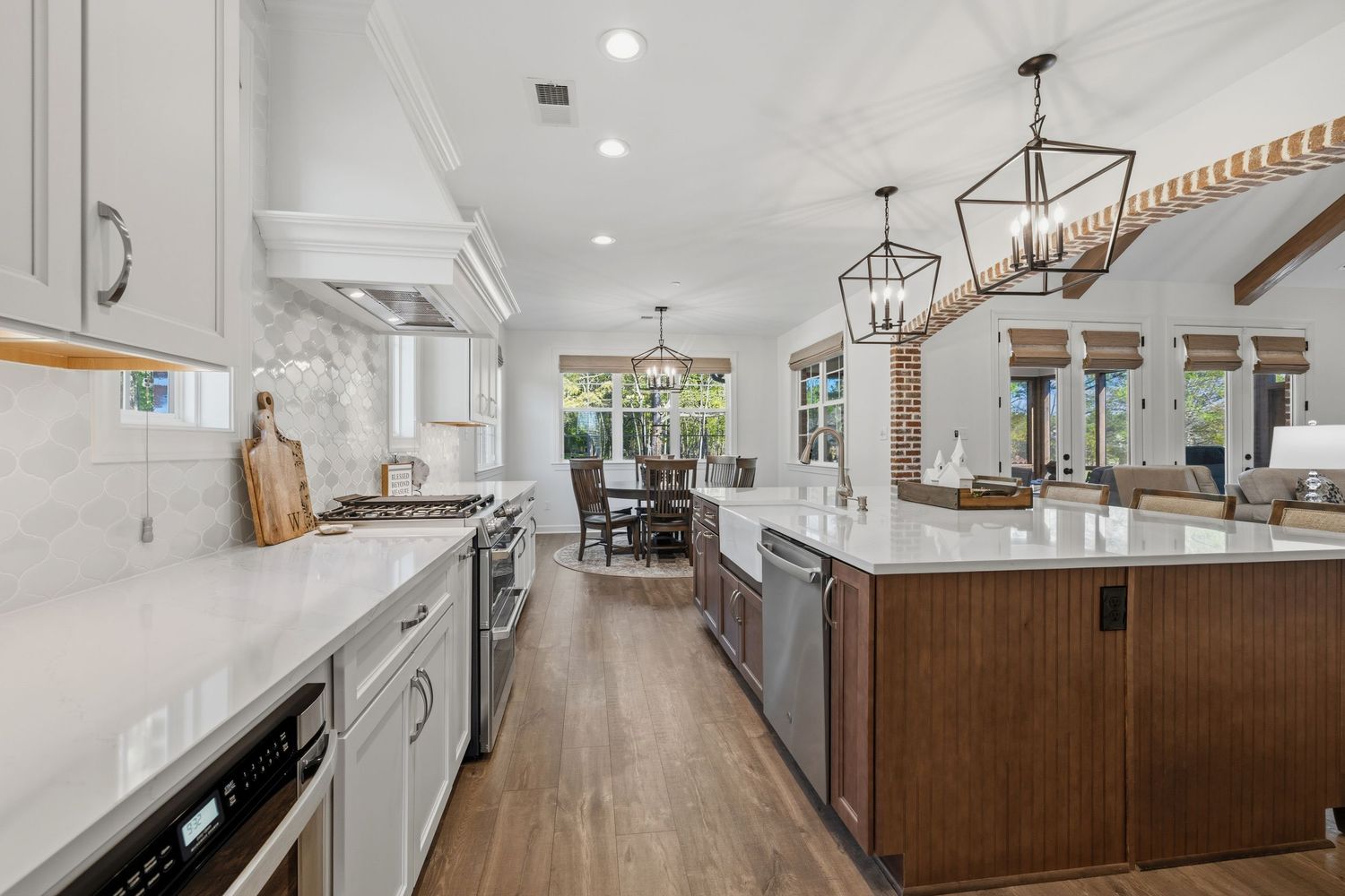 Modern kitchen with white cabinets, marble backsplash, wood island, pendant lights, and stainless steel appliances.