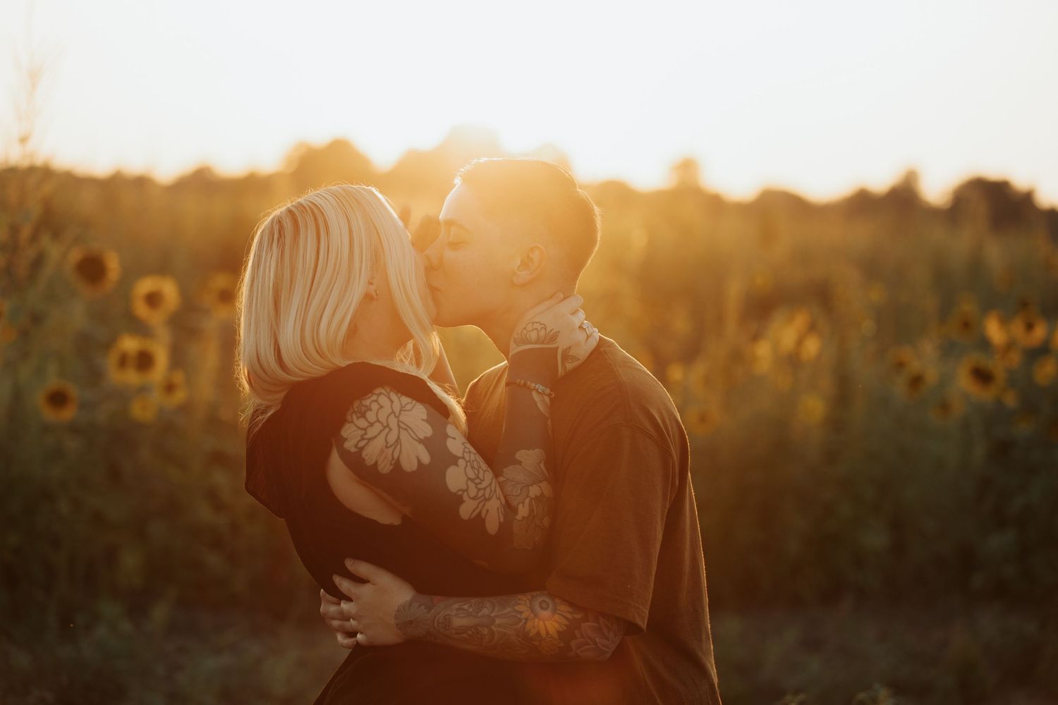 Golden sunlight streams through a romantic scene in a late summer sunflower field.