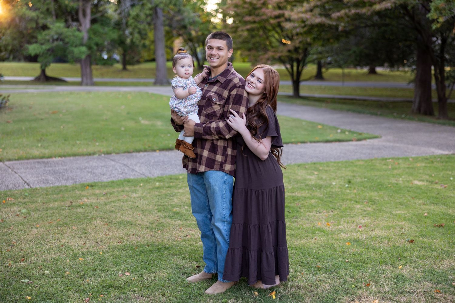 A family stands together on a grassy lawn during golden hour.