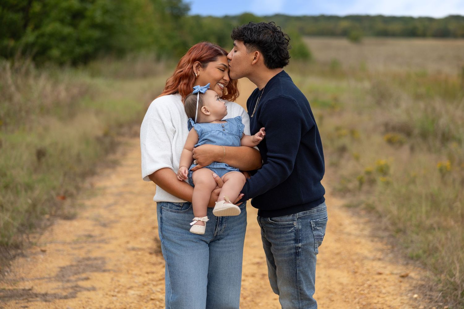 Sweet family moments photographed on a rustic dirt path with wild grass and blue skies.