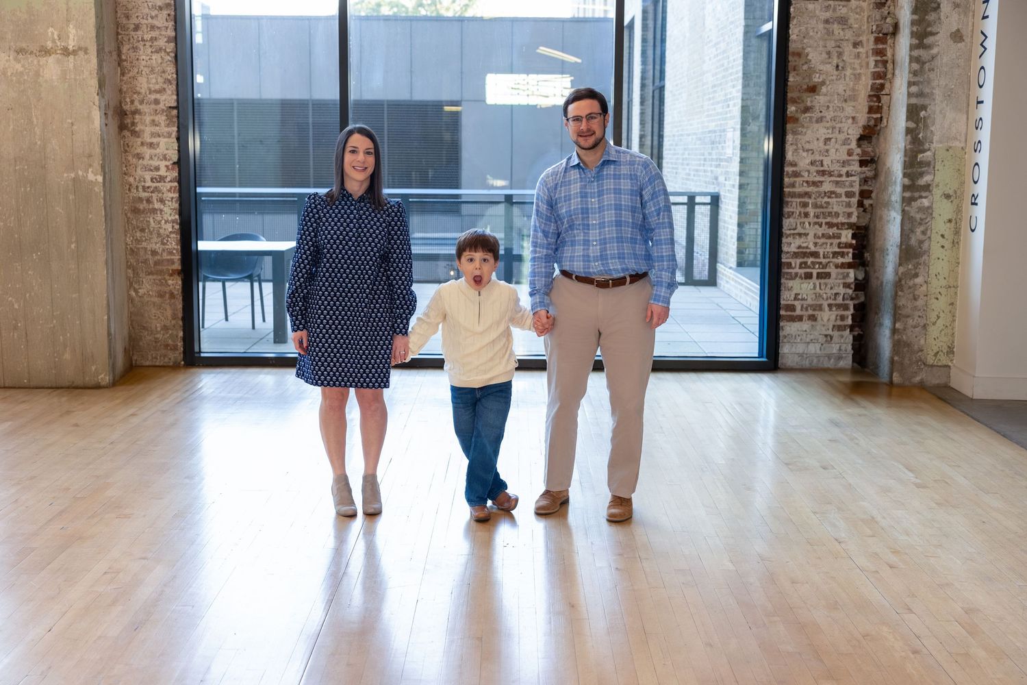 Family standing in a bright industrial space with brick walls and hardwood floors.