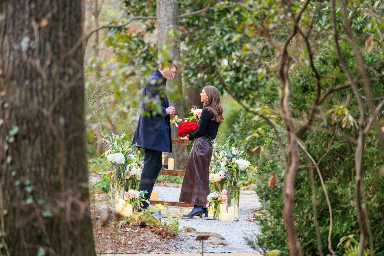 Two people walk along a wooded trail with backpacks while enjoying a sunny autumn day in nature.