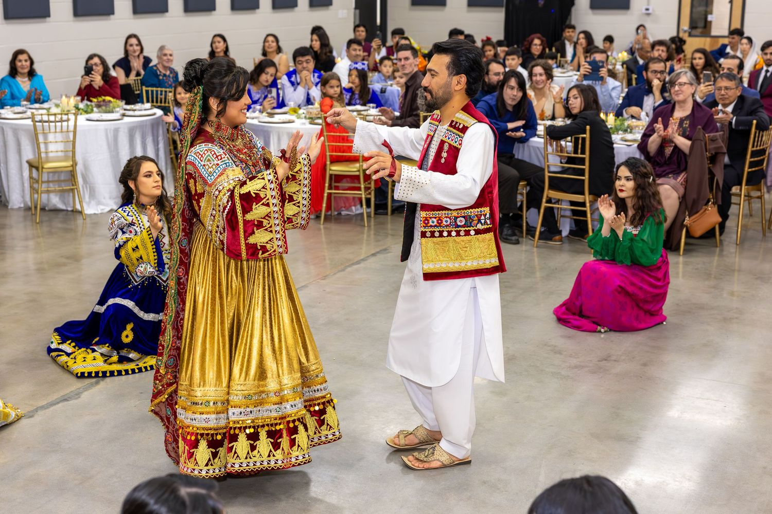 Festive wedding reception with guests in colorful traditional Indian outfits dancing together.