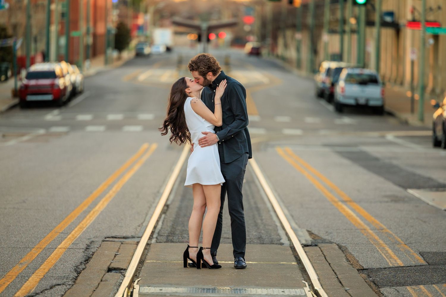 A couple shares a romantic kiss on empty city streets while wearing formal attire.