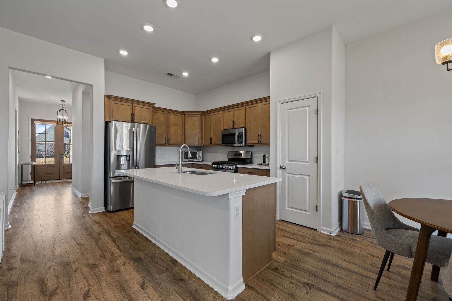 Open concept living space with hardwood floors showcases modern dining area and kitchen with wooden cabinets.