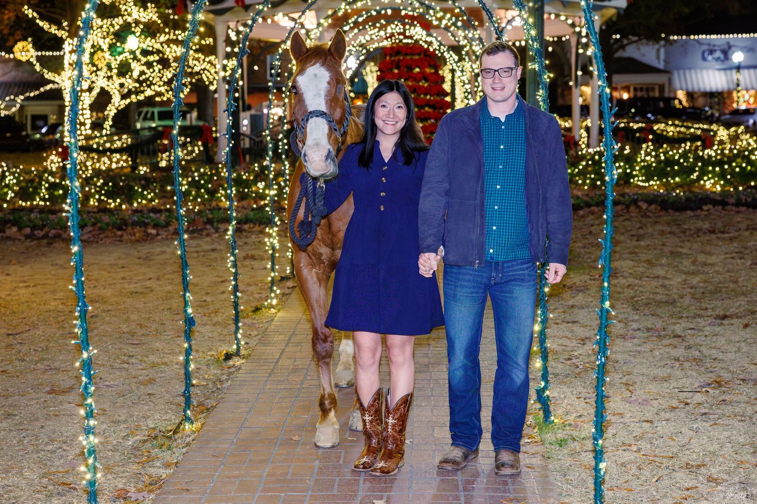 A group poses in front of festive holiday lights and decorations at an outdoor event.