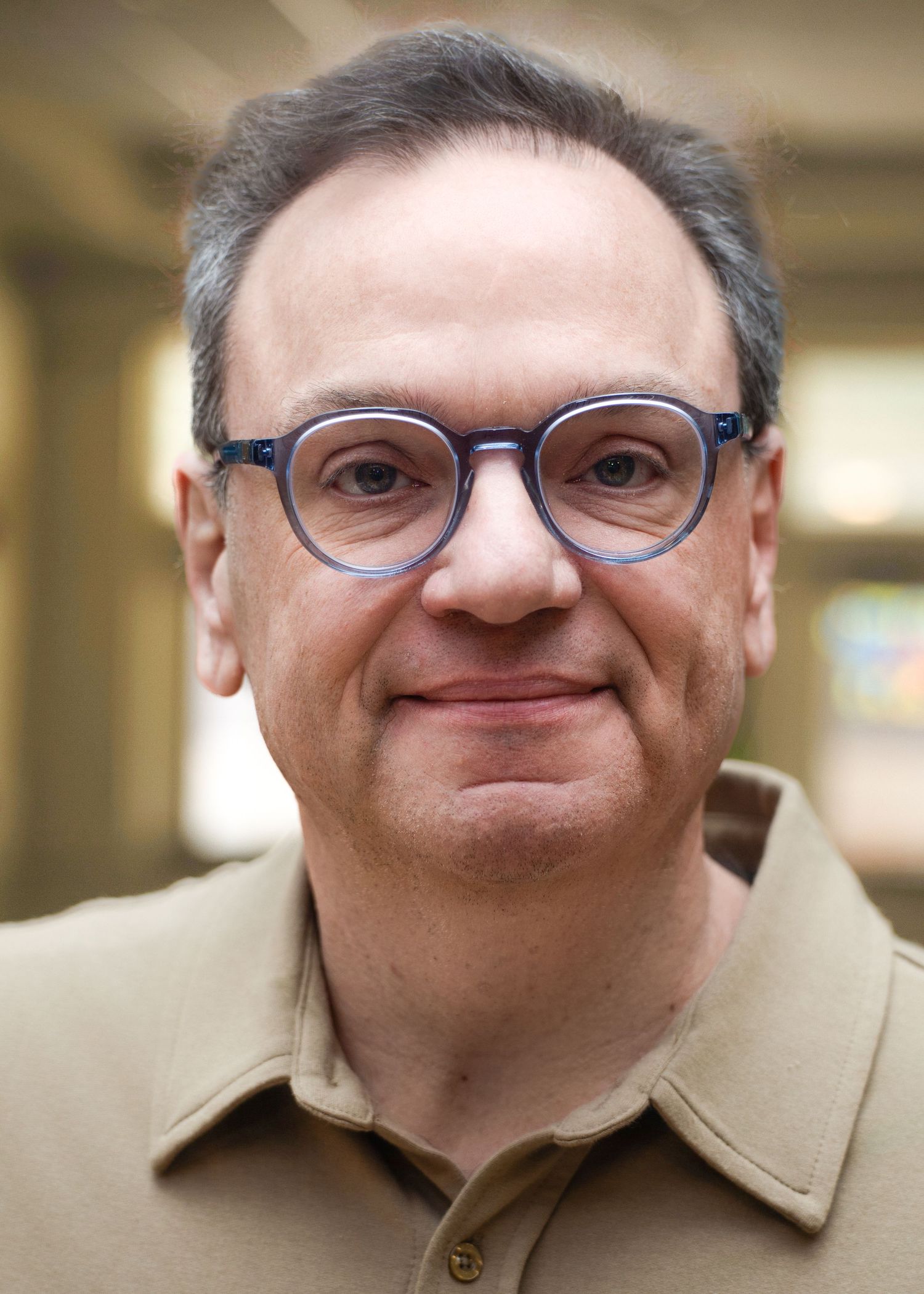 A series of close-up portraits showing progressive expressions from neutral to smiling in a tan collared shirt.