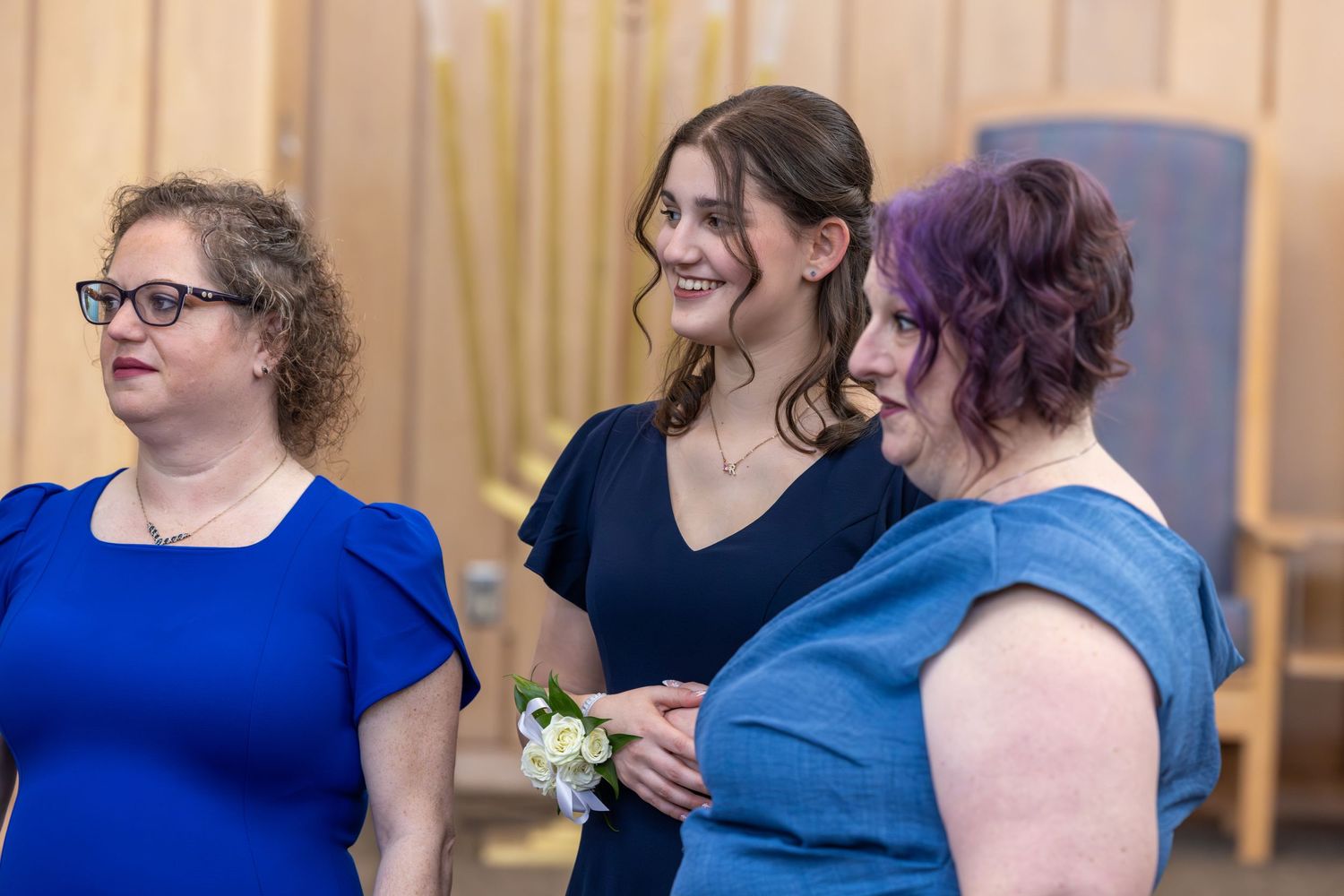A group of people wearing blue and black attire gather together in a casual indoor setting.