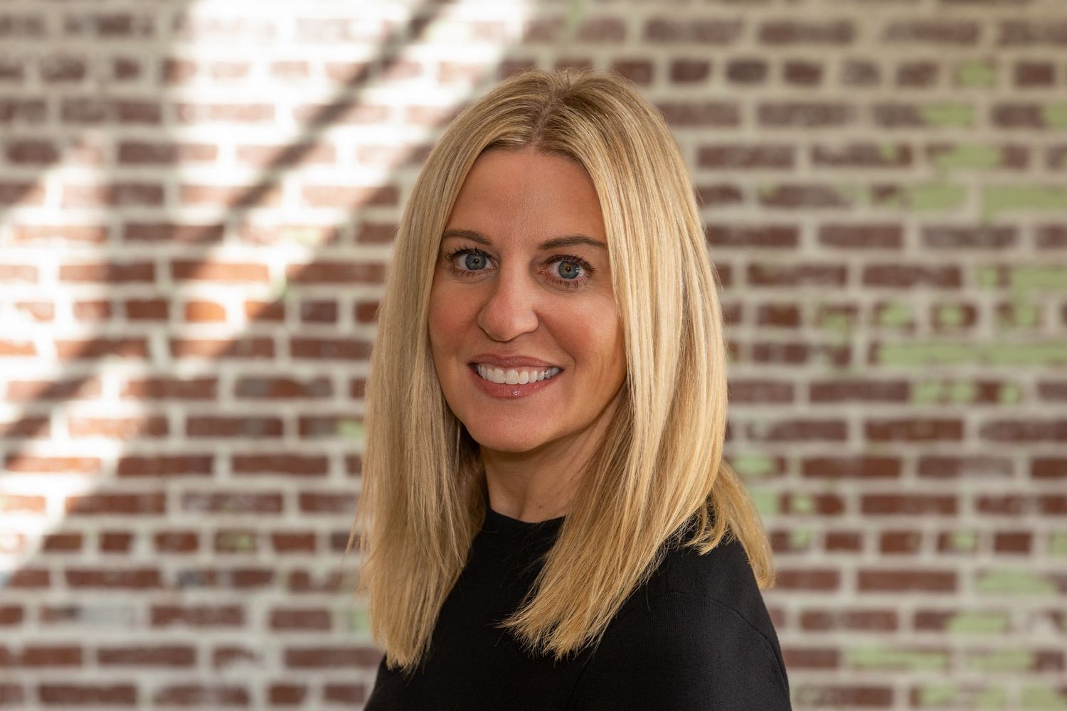 Professional headshots showing different expressions against a rustic brick wall background.