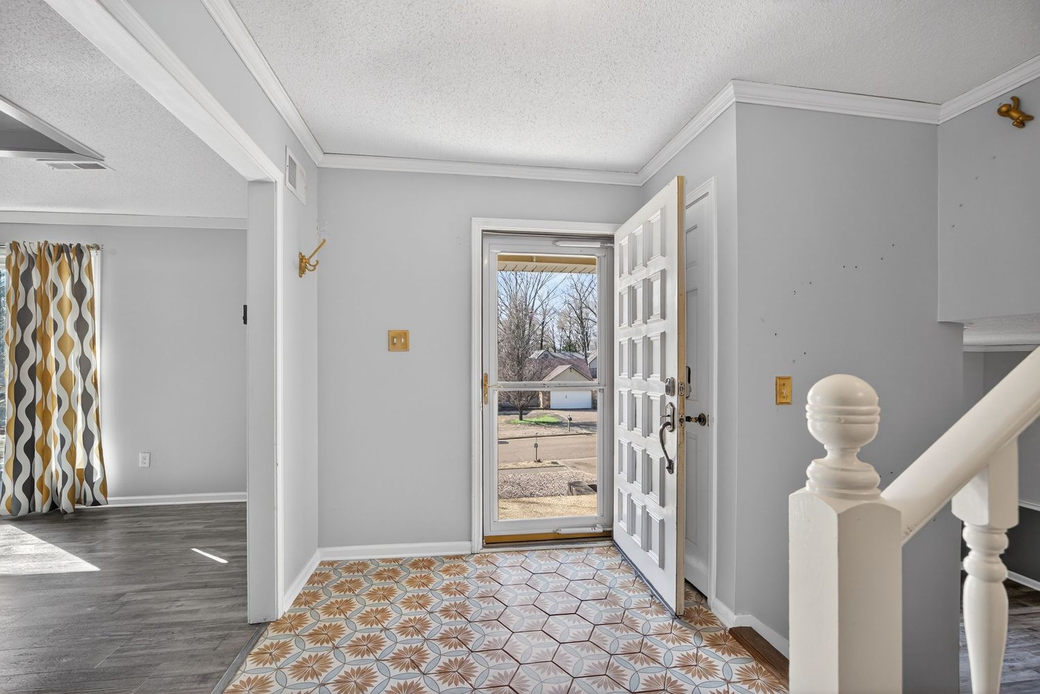 Modern hallway with light gray walls, white crown molding, and hardwood flooring leads to multiple doorways.