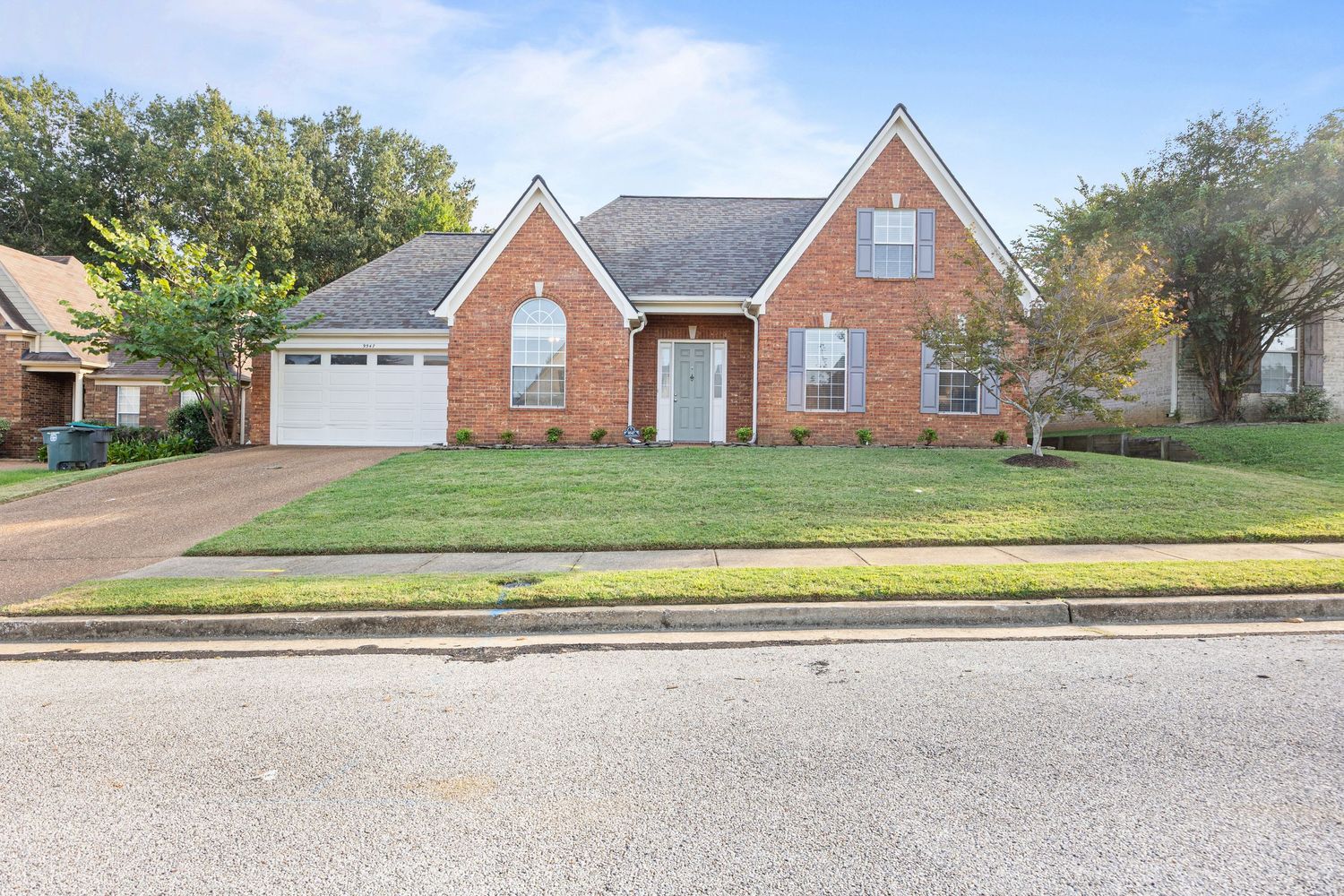 A collage of red brick suburban houses with well-maintained lawns and driveways on a residential street.