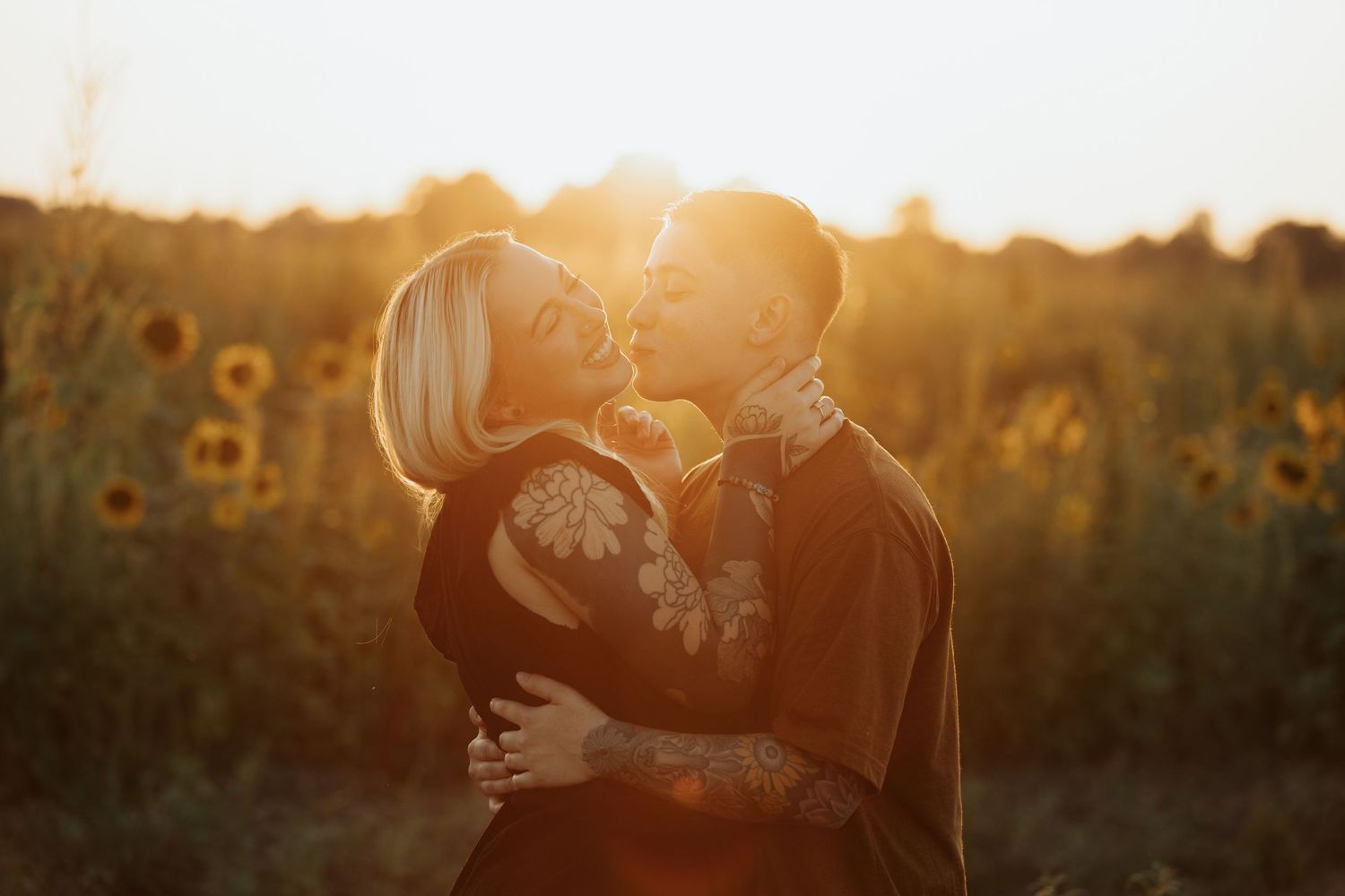 Dreamy sunset portrait of an embrace amidst towering sunflowers.