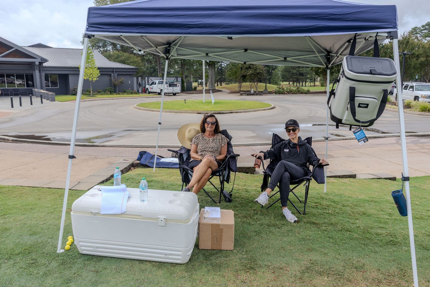 Event tent setup with supplies and seating on a golf course.