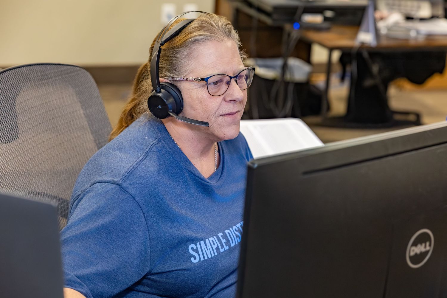 Customer service representative wearing headset while working at computer desk.