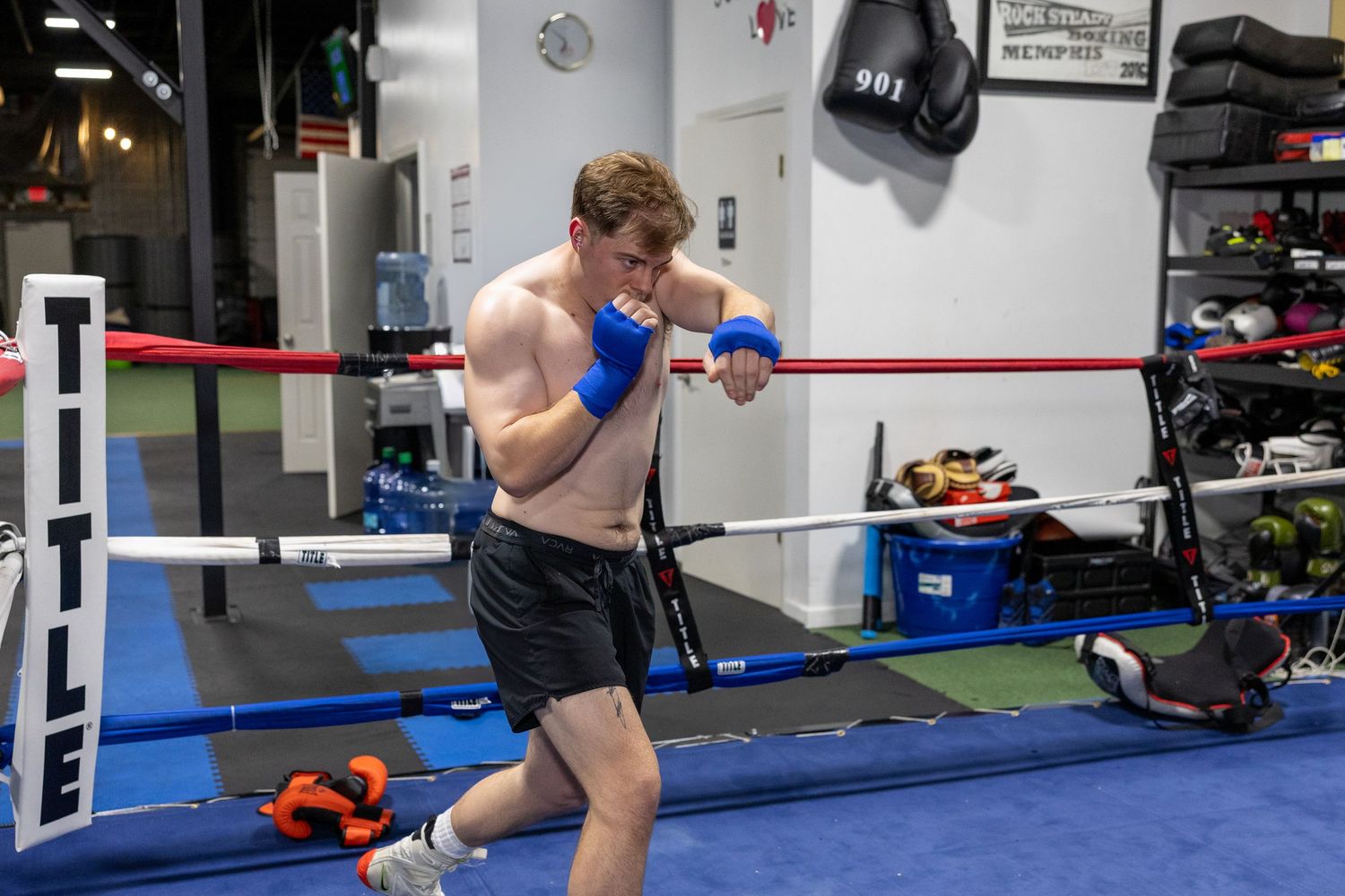 Boxer training with punching bags in a professional gym facility.