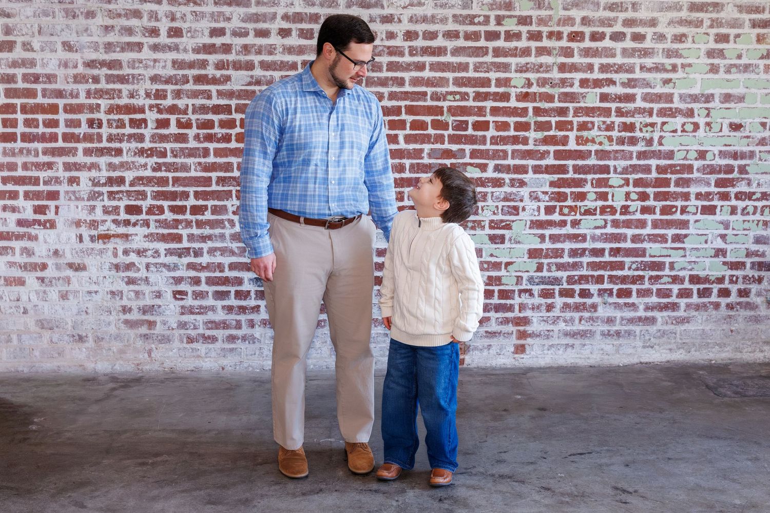People standing together against rustic brick wall in casual attire.