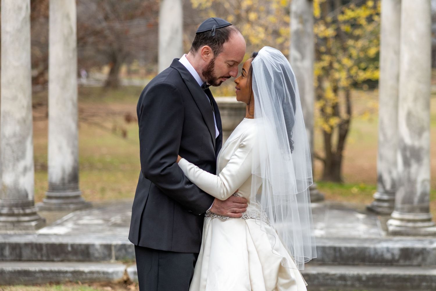 Romantic wedding portrait taken outdoors among classical stone columns.