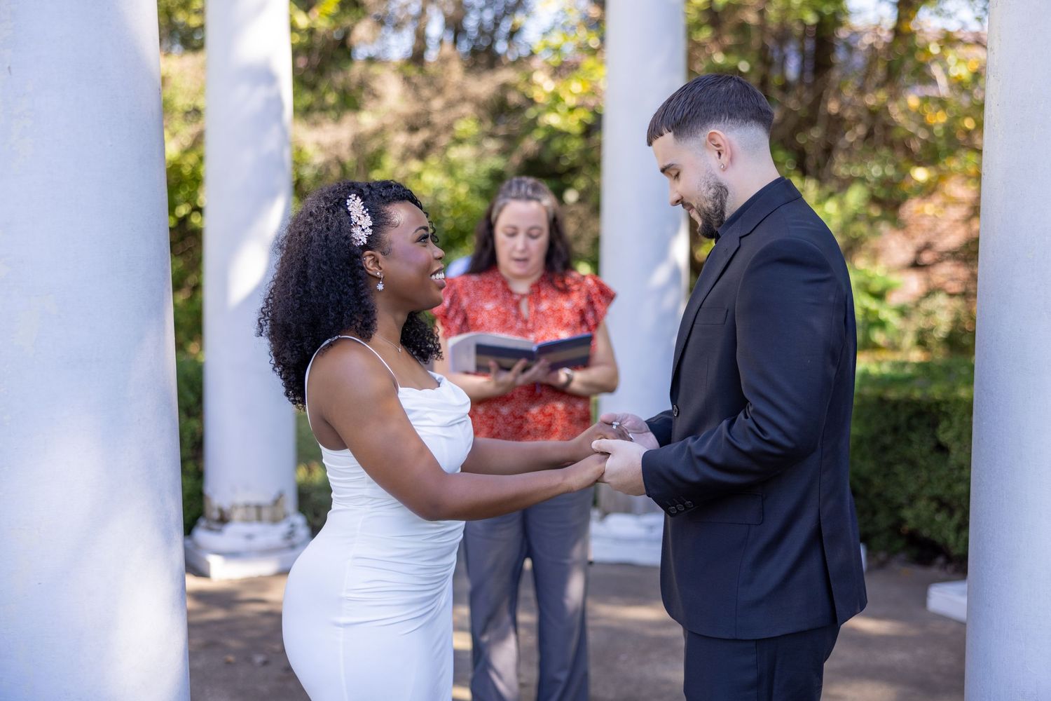 Wedding ceremony moments captured between white pillars with guests in attendance.
