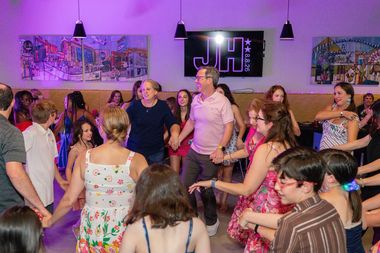 People dancing and socializing at an energetic indoor event with colorful artwork on walls.