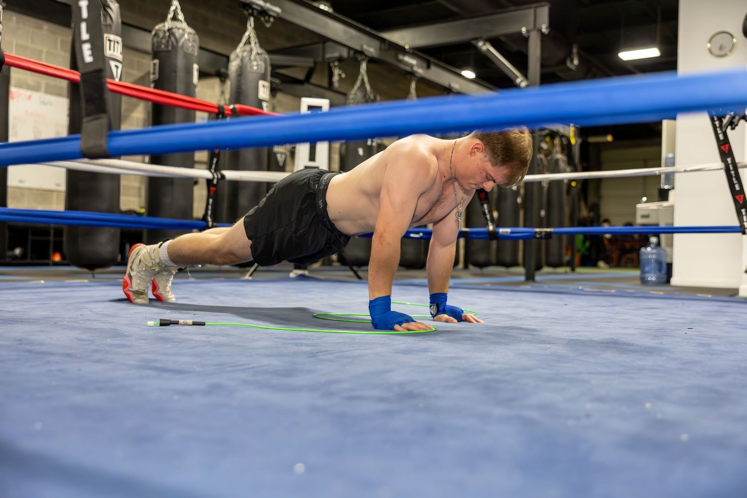 Blue boxing ring mat with ropes visible in a training facility.