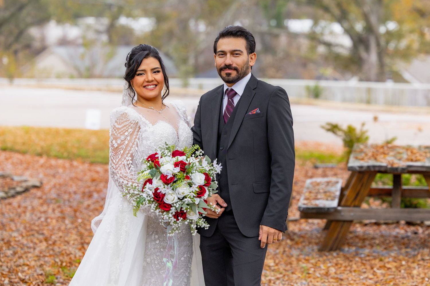 A beautiful autumn wedding photoshoot featuring a couple in a white lace dress and black suit among fall foliage.