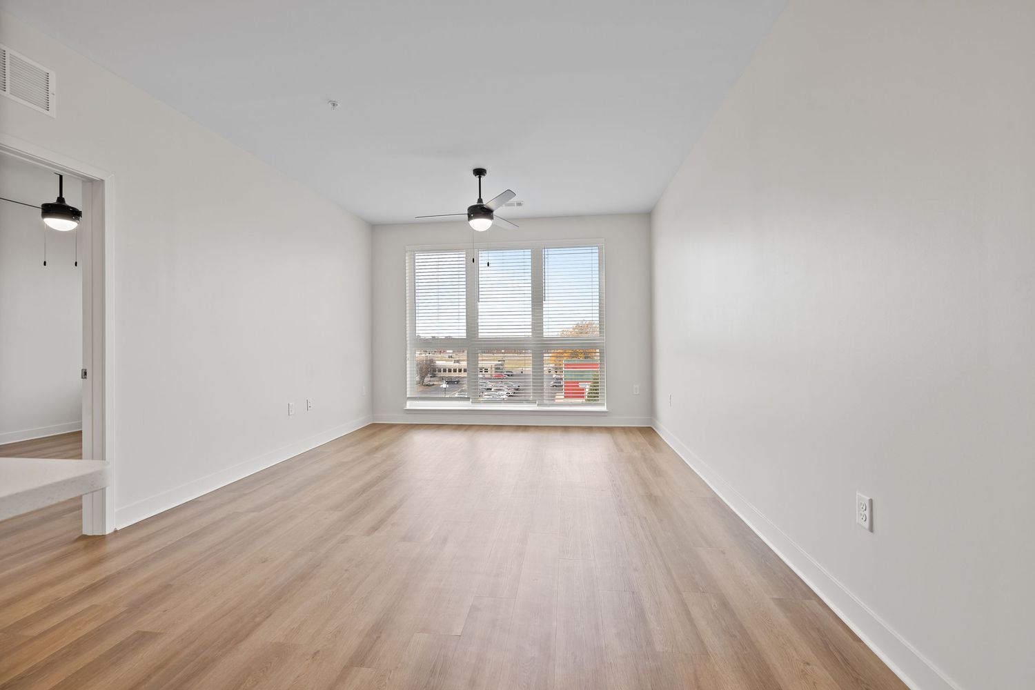 Bright open living area with hardwood flooring and large windows at the far end.