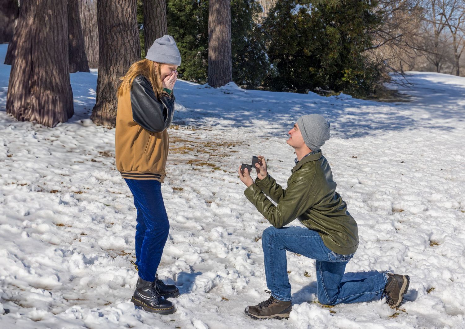 A winter proposal scene with someone kneeling in the snow to pop the question.