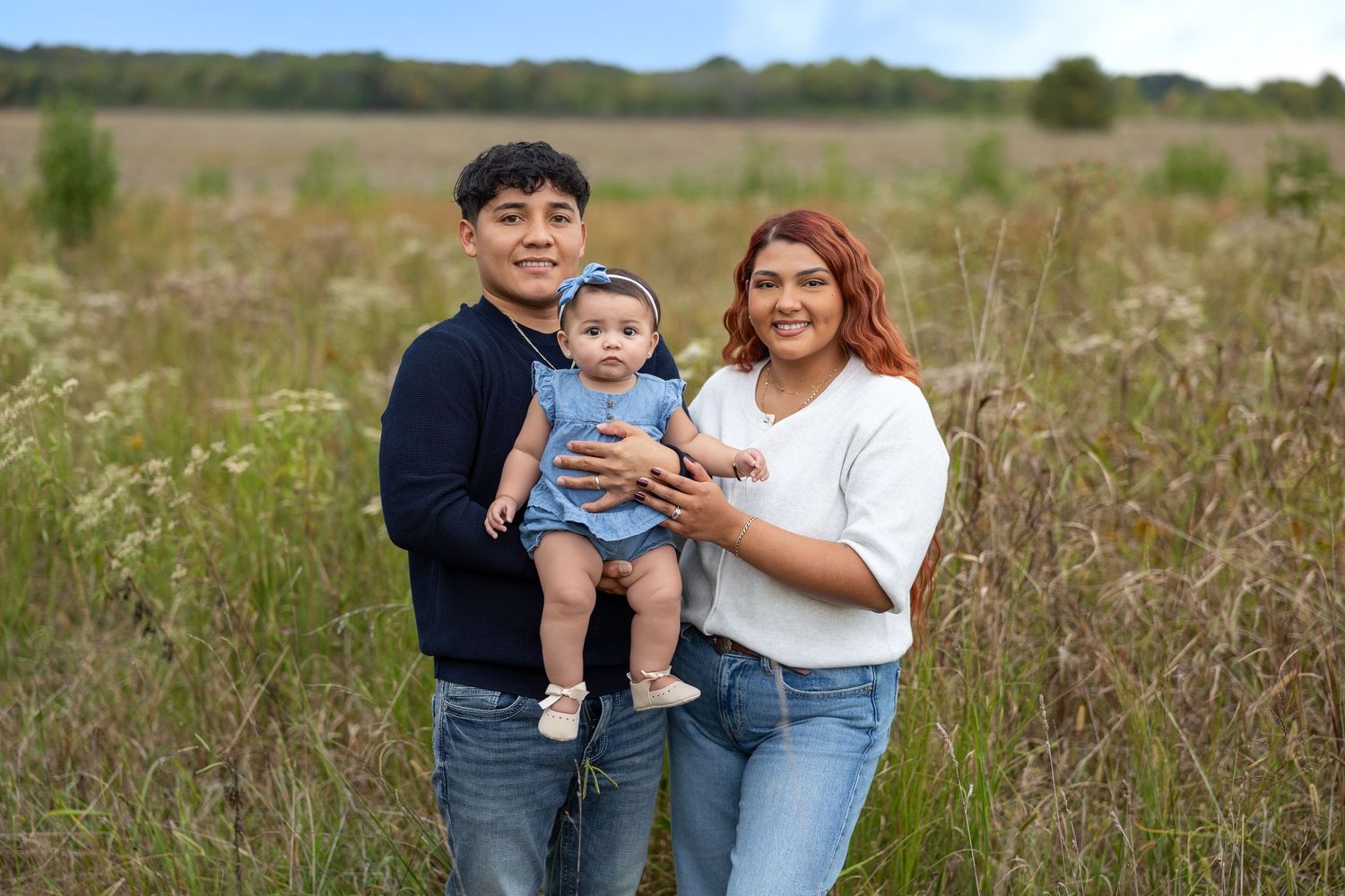 Natural light family photography session in an open field with green vegetation.