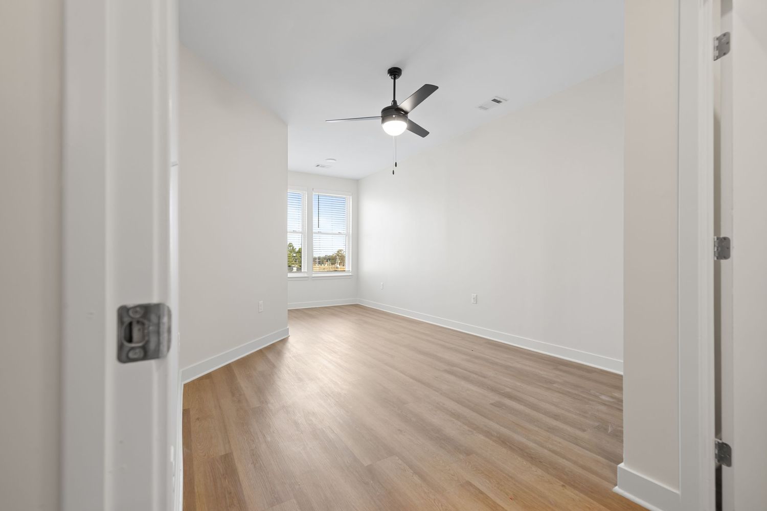 Long hallway with hardwood flooring and large windows providing natural light.
