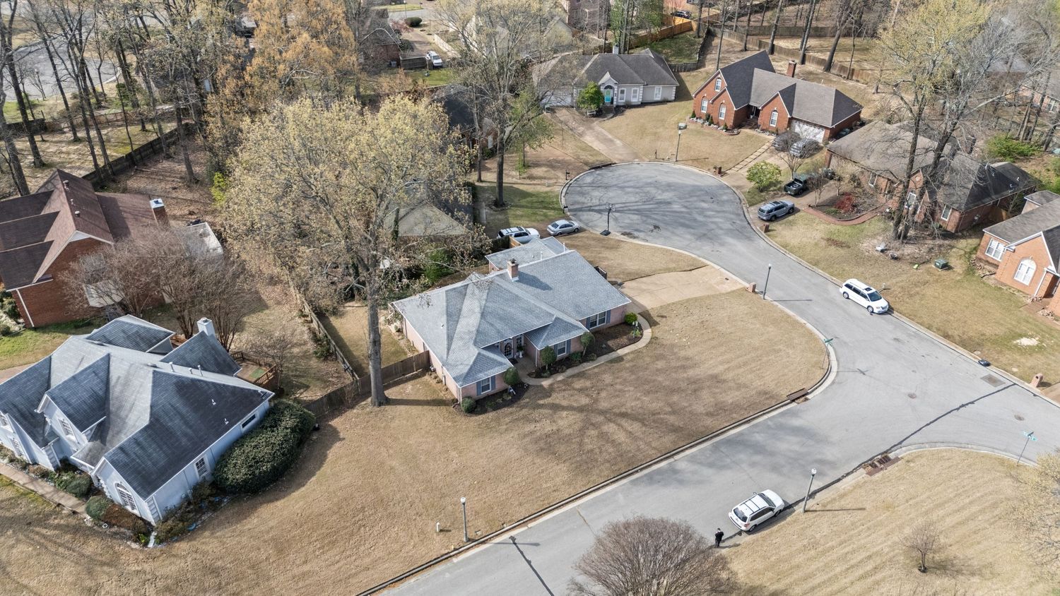 Aerial panoramic view of a suburban neighborhood with houses, trees, and winding streets during autumn season.
