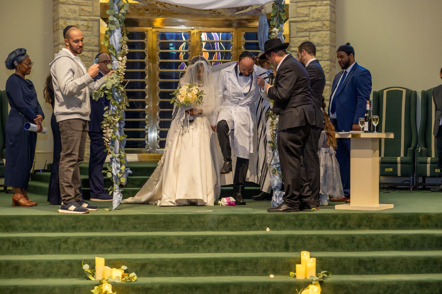 Wedding ceremony setup with yellow lanterns decorating green carpeted steps.