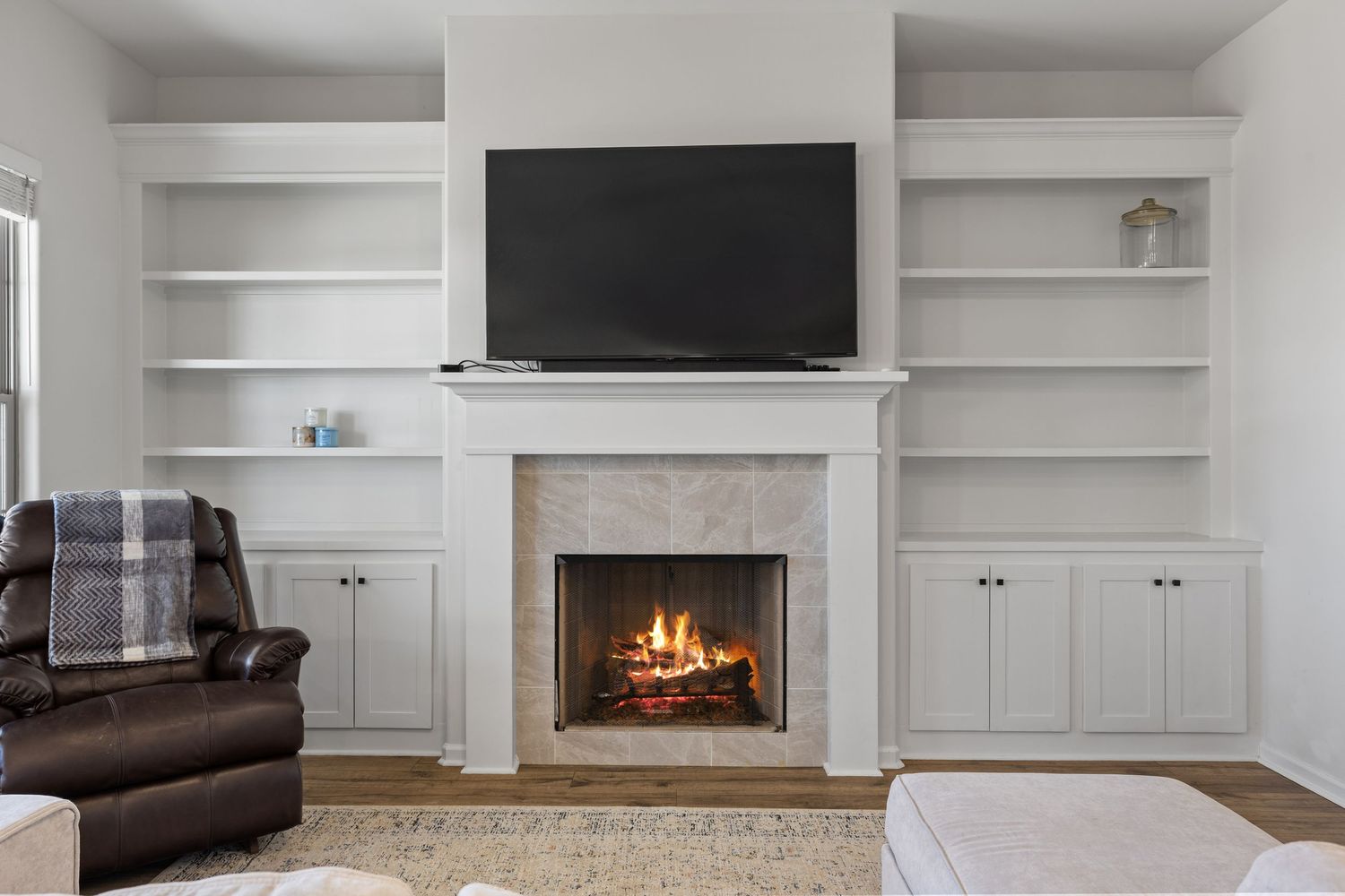 Modern white built-in entertainment center with fireplace, floating shelves, and cabinets in a contemporary living room.