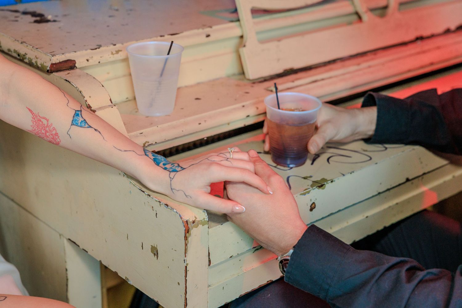 Hands reach across a distressed white wooden table with a beverage in the background during a casual moment.