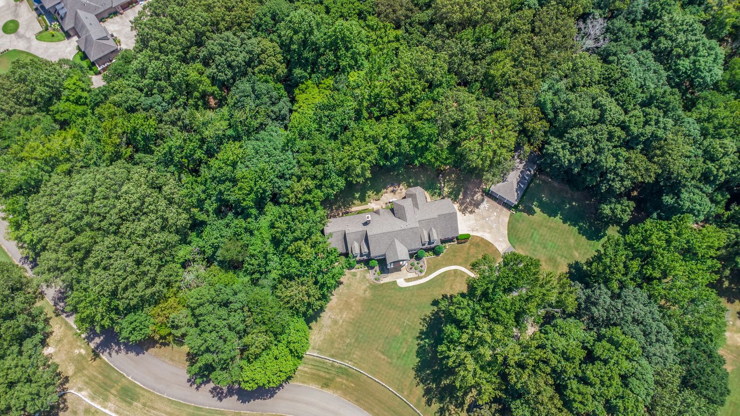 Aerial view of a lush green golf course with winding paths and scattered trees surrounded by residential areas.