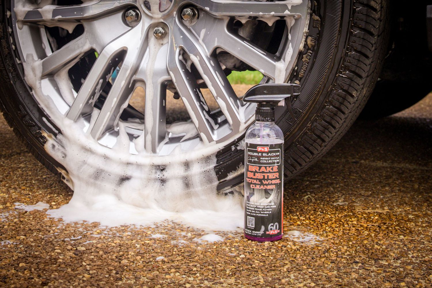 A car wheel spraying white smoke during a burnout on a dirt surface with dramatic lighting effects.