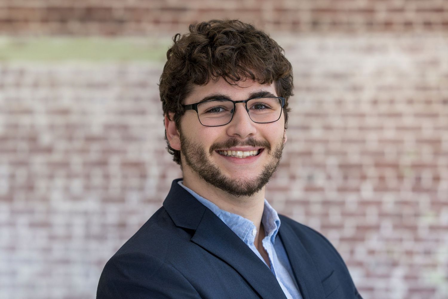 Professional headshot portraits against a brick wall background showing different expressions in business attire.