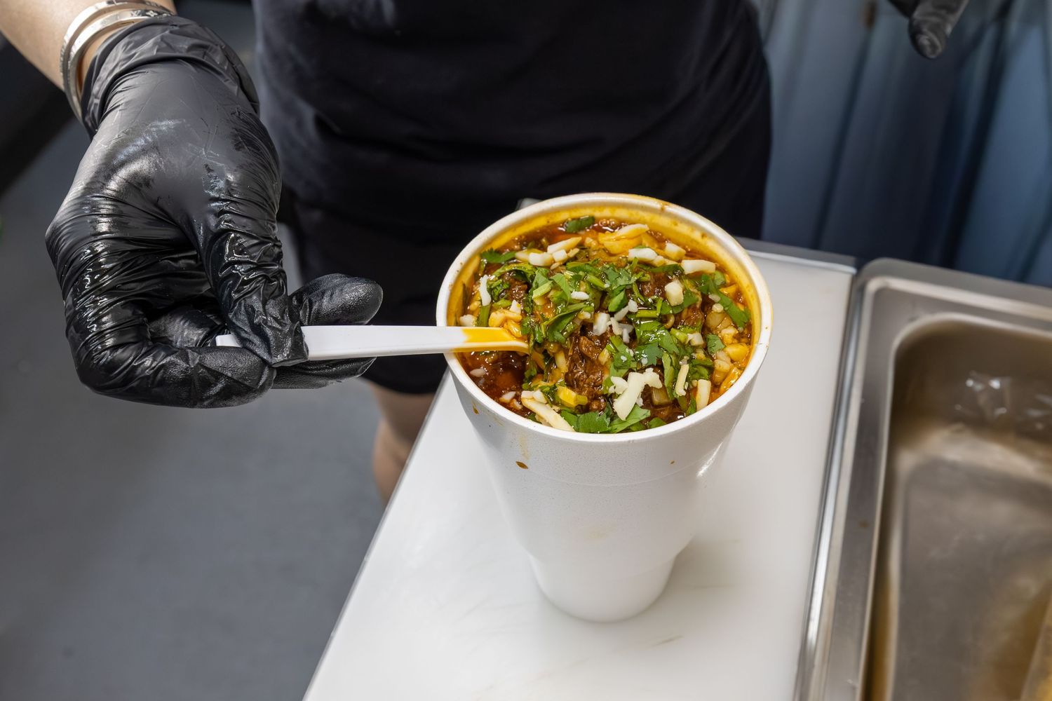 A steaming bowl of Vietnamese pho noodle soup garnished with fresh herbs and green onions in a restaurant setting.